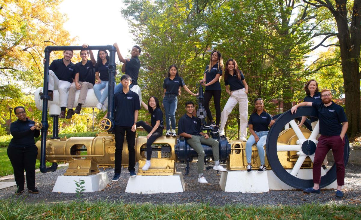 students in front of steam engine on campus